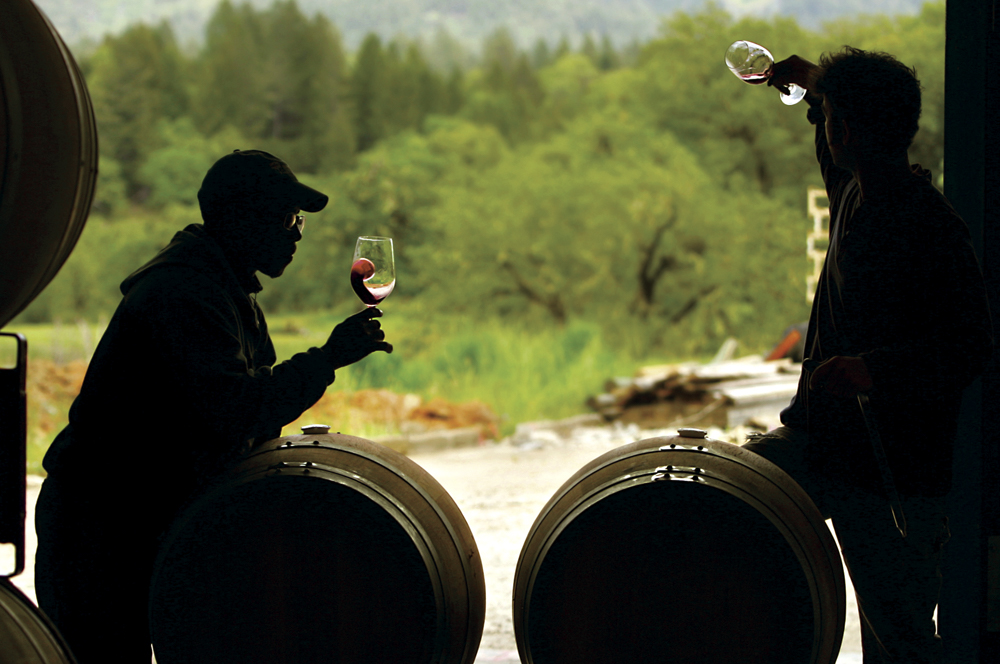 two people barrel tasting red wine