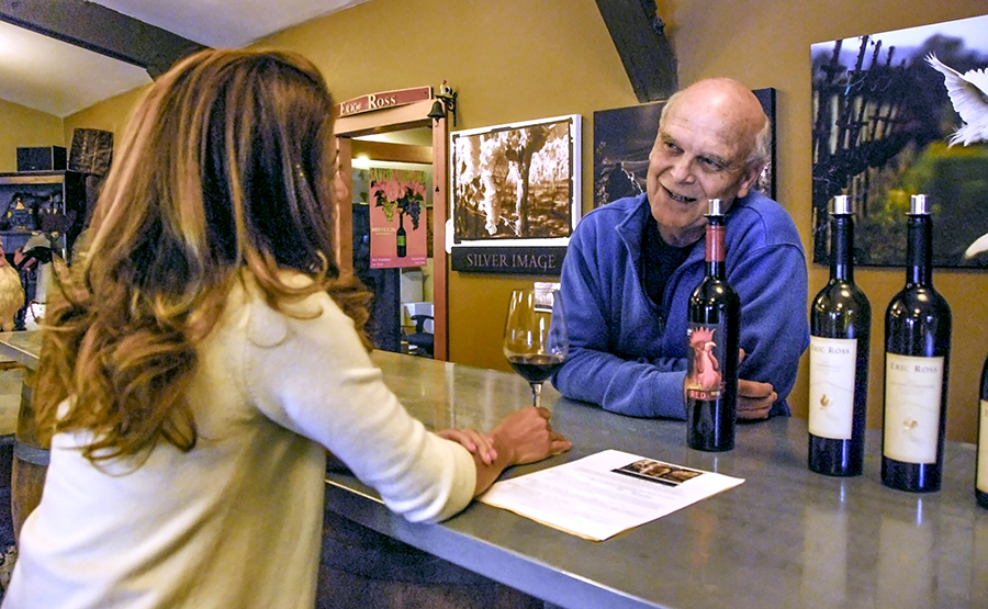 Eric pouring wine and talking to a visitor in the tasting room